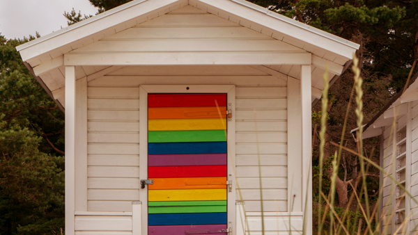 Seaside cabin with rainbow coloured door.