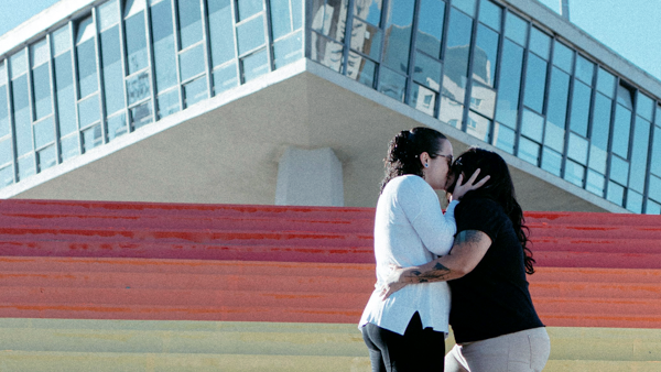 A same-sex couple kissing on a rainbow-painted stairs.